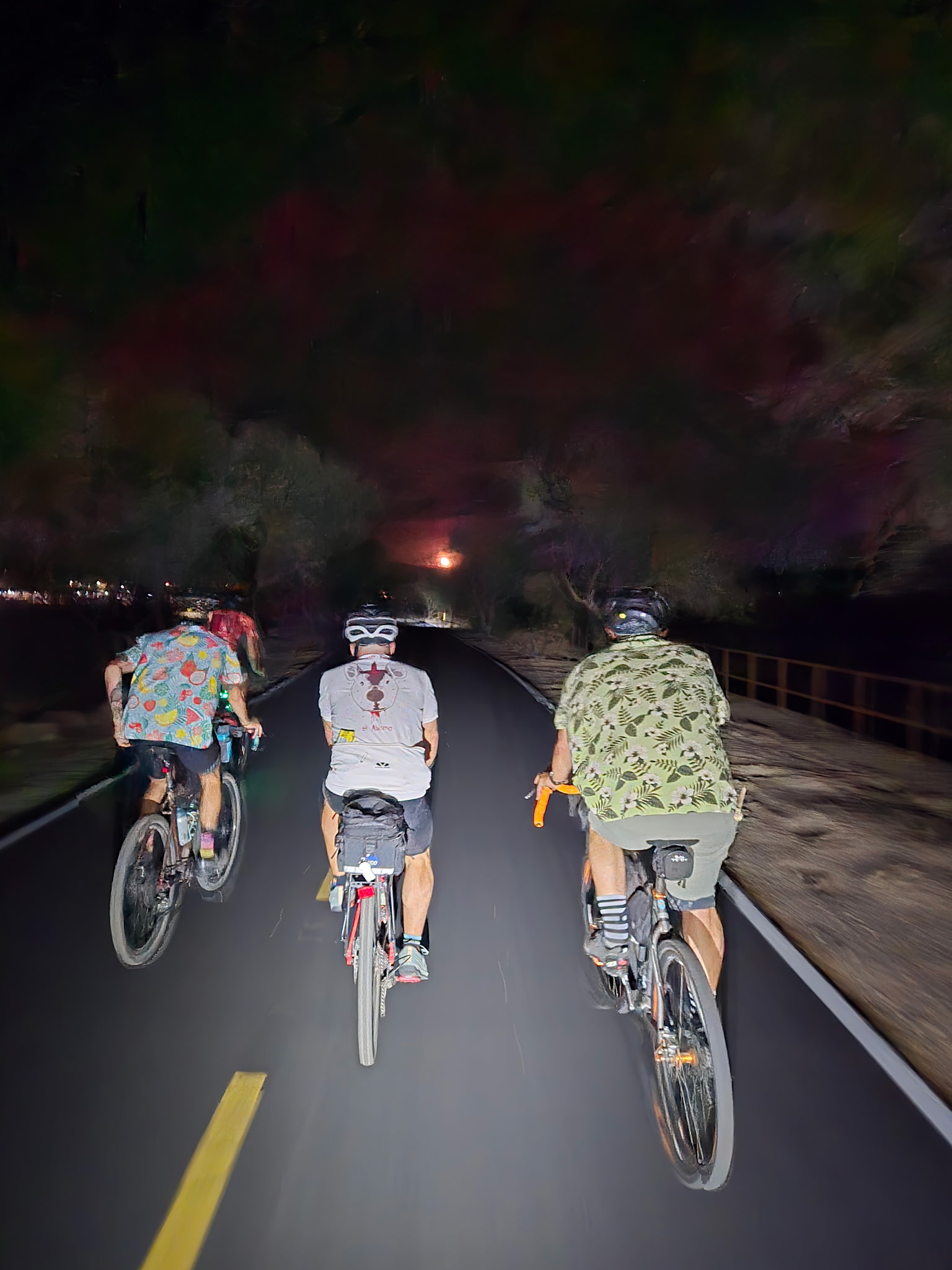 Three riders in a paceline on a dark trail, moonrise glowing ahead of them.