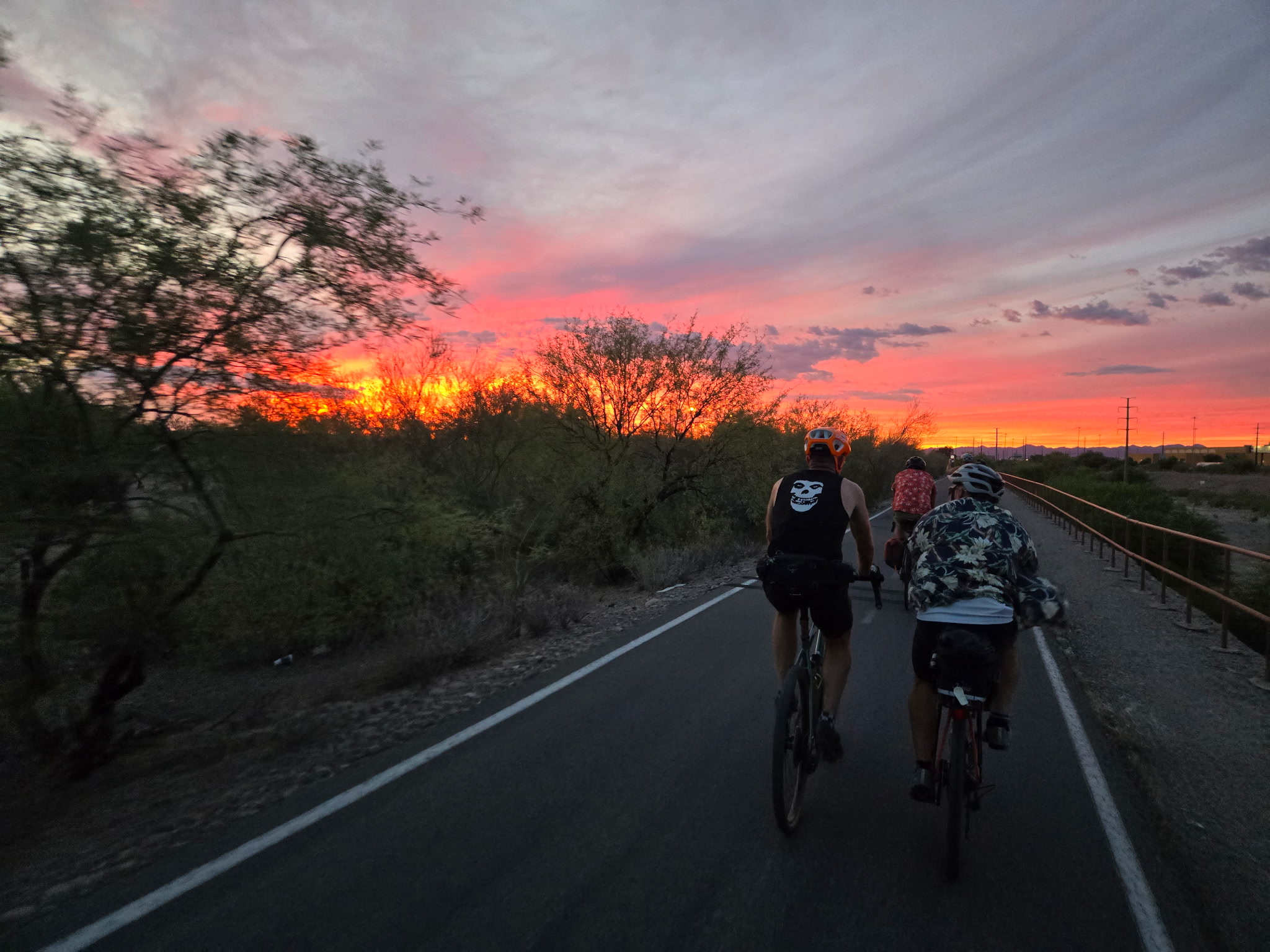 Riders pulling away from Transit into an orange and violet Tucson sunset, first night of the ride.